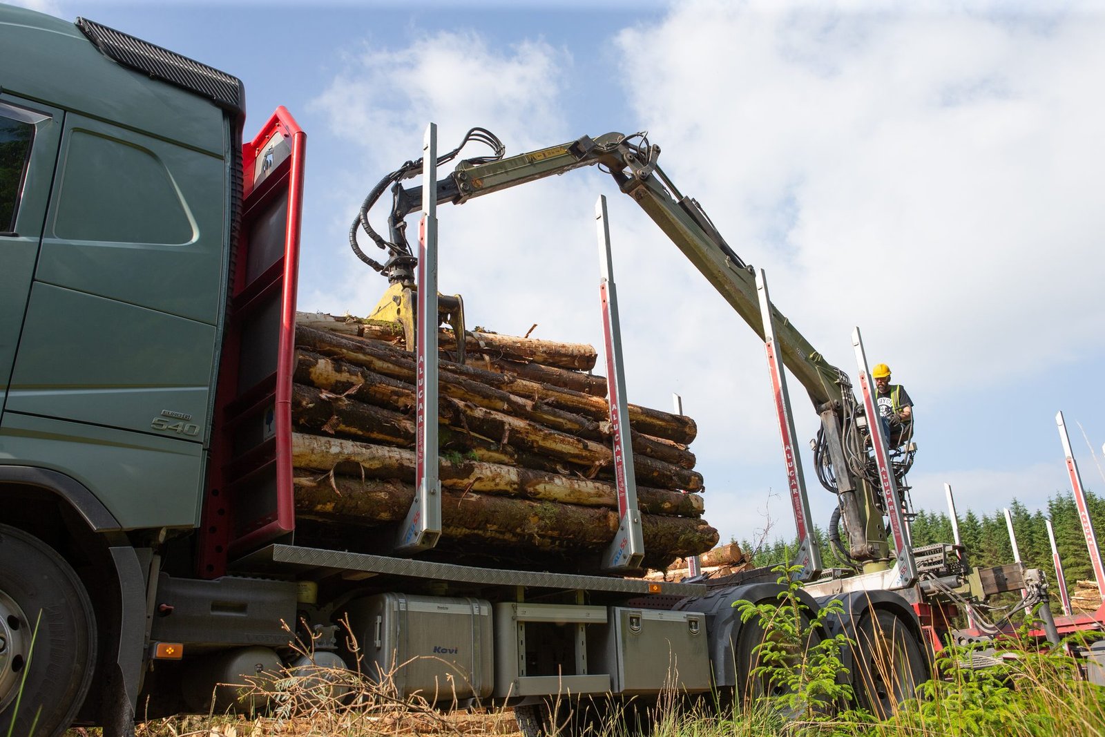 Crane grapple loading cut logs onto a forestry trailer