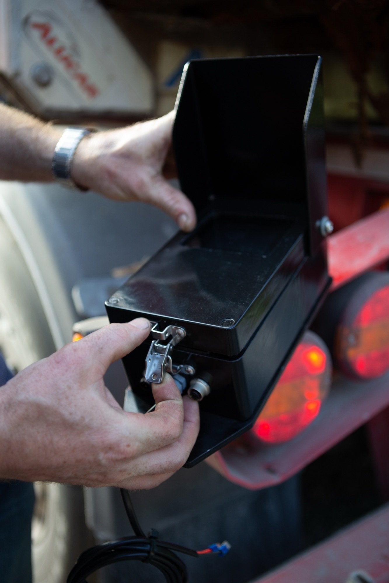 Hands opening a WeighPro printer display unit on a trailer