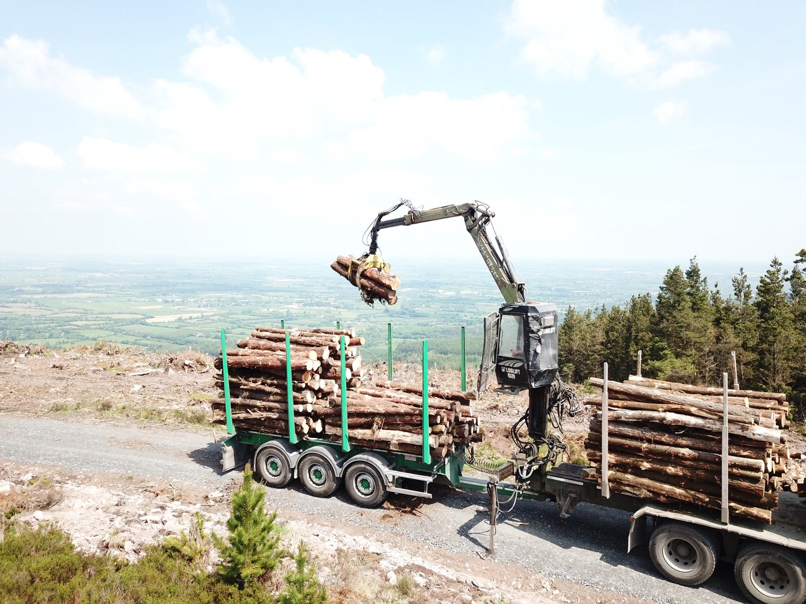 Aerial view of crane loading timber on hillside